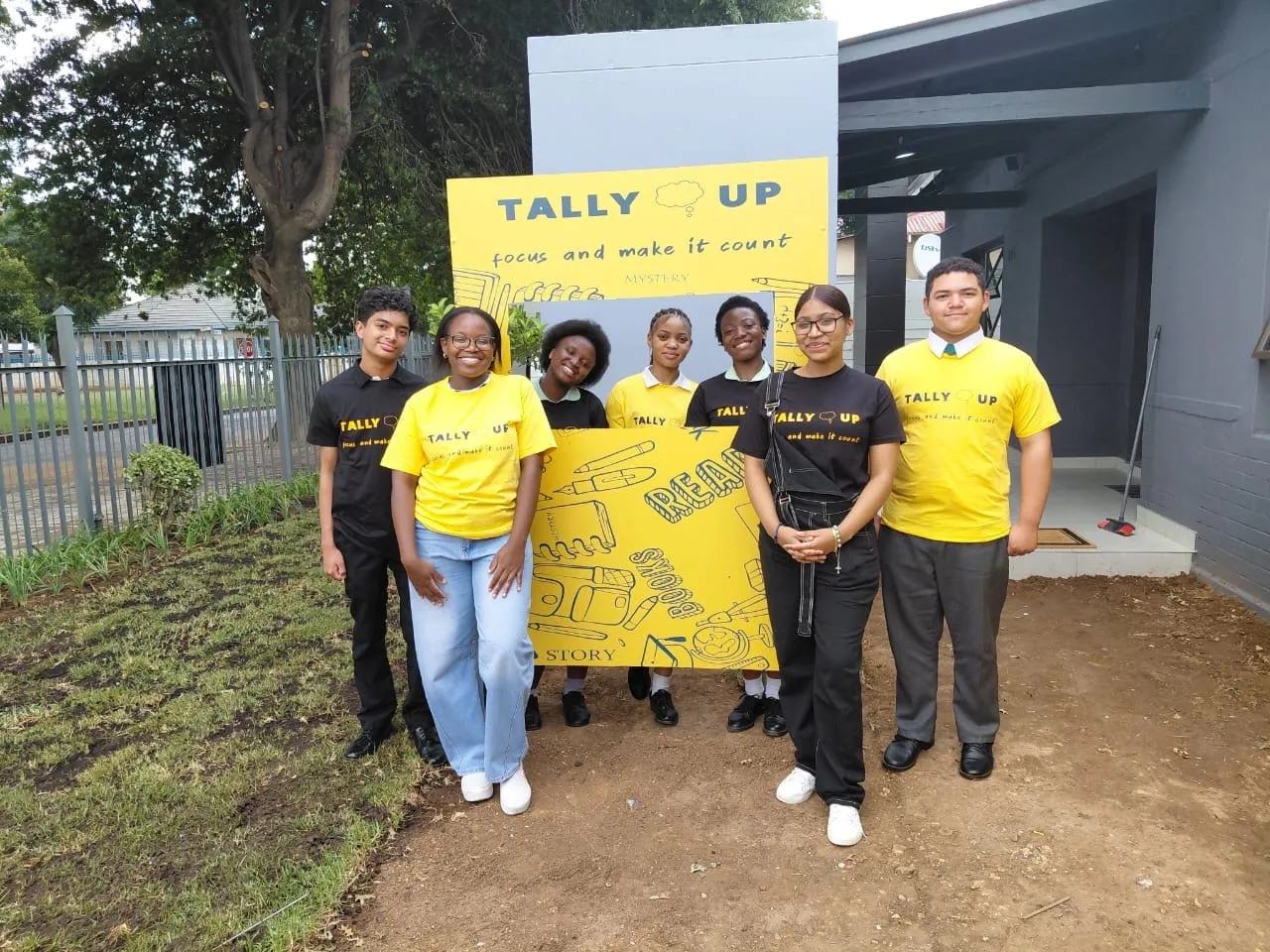 The Tally Up team outside the centre in yellow and black shirts